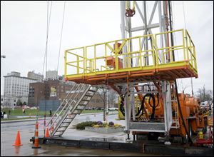 A large drilling rig sits outside the Covelli Center with some of the Youngstown, Ohio skyline in the background.