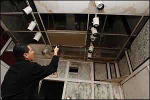 Wood County building official Michael Rudey shines a flashlight at a hole in the ceiling, which has resulted in black mold on the walls, during an inspection of Woodville Mall in Northwood.