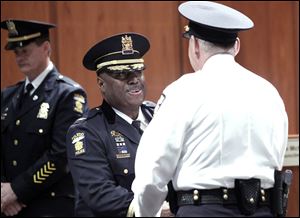 Police Chief Derrick Diggs congratulates Sgt. Ronald Frederick after he receives his new rank of lieutenant in the Toledo City Council chambers. Chief Diggs said the new officers were ‘part of a new breed.’