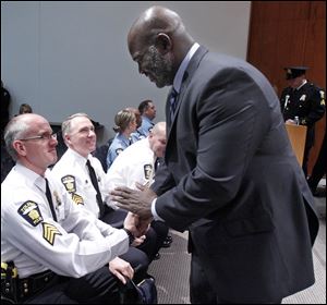 Toledo Mayor Mike Bell congratulates Sgt. Richard Hoover, center, and Sgt. Phillip Cook, right, on attaining their new rank of lieutenant. Seven men and one woman received promotions.