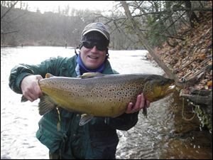 Steelheader Ed Nowak (left) of Akron beams with pride at the whopping, 13-pound brown brook trout he took at Oak Orchard River, a Lake Ontario tributary. 