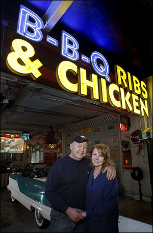 Chuck Hymore and girlfriend Teresa St. Marie stand below a neon sign he salvaged from a junkyard.