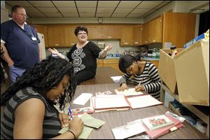 Lisa Kronbach-Eisenbach, center, director of Nightingale's Harvest, speaks to volunteer staff members Lyntoya Carson, foreground, and Raechel Walker while her husband, Kenny Eisenbach, stands by.