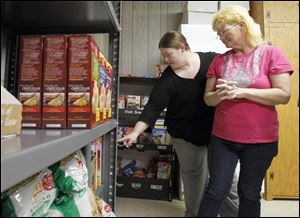 Mary Blair, left, helps her mom, Erma Oswalt, select food to take home while at Nightingale's Harvest food pantry at St. James Lutheran Church in Sylvania. The pantry helps people who, like Ms. Oswalt, have cancer.