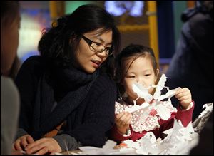 Yunju Seo of Bowling Green admires the snowflake produced by her daughter Somin Jin, 6, as they attend a workshop led by Dr. Snowflake at the Imagination Station in downtown Toledo.