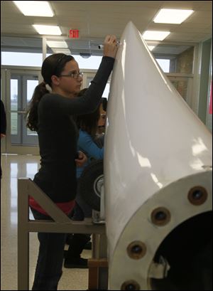 Kendall Wells, a sixth grader, signs a wind turbine blade.
