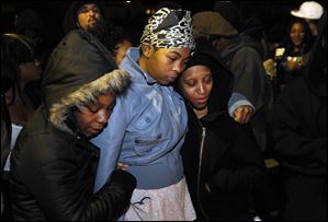 Cousin Antoinette Tilman, left, sister Shavone Belcher, and girlfriend Mariah Livingston hug near a memorial on the corner of Tecumseh and Hoag in honor of Deadrick Rocker, the city's 38th homicide victim.
