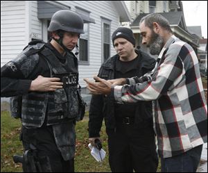 Police listen as Gary Cluckey, who lives on the first floor at 317 Western Ave., explains the layout of the house and the steps to the third floor.