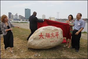 Toledo Mayor Mike Bell, Tina Yuan, and Wu King Hung unveil a symbolic rock at the Marina District. Dashing Pacific, a group of Chinese investors, purchased 69 acres at the east side Marina District in July and The Docks restaurant complex, also in East Toledo, in march.