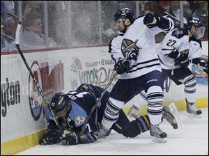 Toledo Walleye player Kyle Rogers (17) is knocked to the ice by Greenville Road Warriors player Jeff Prough (8) during the second period at Huntington Center.