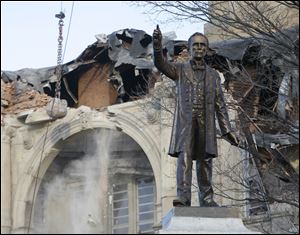 A statue of General William Harvey Gibson stands in the foreground as the Seneca County Courthouse in Tiffin, Ohio,  is demolished.