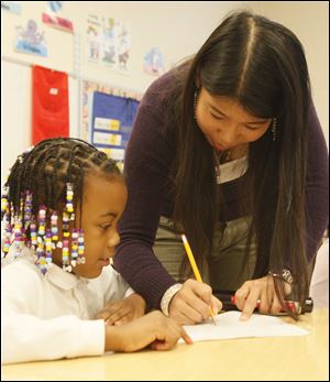 First-grader Aaliyah Brown gets some help writing a Chinese word from teacher Tana Bai at Old Orchard Elementary School in Toledo.