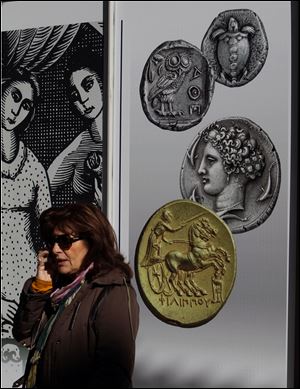 A woman speaks on her phone Friday in front of a Greek bank's adverting banner with ancient coins in Athens,.