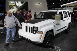 Howell, Mich. residents Pat Dowd, from left, and his sons Colin and Nolan, feel the hood of a Jeep Liberty during the North American International Auto Show in Detroit, Mich.