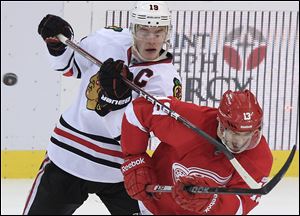 The Blackhawks' Jonathan Toews, left, stick checks the Red Wings' Pavel Datsyuk in which the Red Wings won 3-2 in overtime. Datsyuk had two assists in the 14th straight home win, tying a team record.