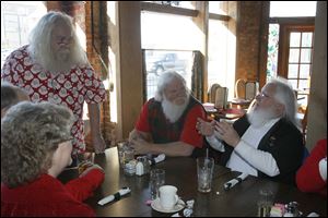 As the Santa Clauses meet, Russell Spice of Sterling Heights, Mich., standing, talks to David Allen of Port Clinton, in the plaid vest, Richard Incledon of Perrysburg, right, and Mary Miller of Toledo, foreground.