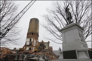 Wrecking crews are to continue trucking away debris from the courthouse while delaying the start of razing the clock tower.