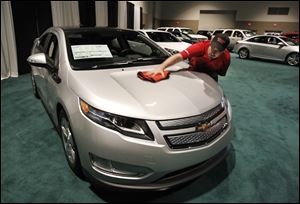 Robert Freeman of the Los Angeles-area firm Professional Detailers Inc., which specializes in preparing vehicles for auto shows, shines the hood of a Chevrolet Volt at SeaGate Convention Centre.