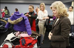 Kelly Marable, a day-care caseworker for Lucas County Children Services, left, elects coats for her clients Tuesday with the help of Kroger Co. employees Jackie Siekman and Kathy Smith, right, at the Children Services building on Adams Street. 
