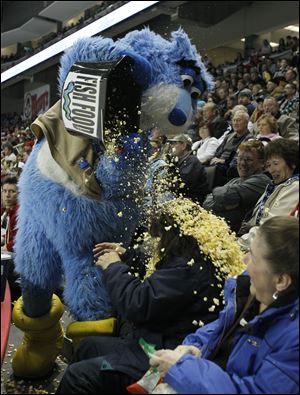 Toledo Walleye mascot Cat Trick dumps a bucket of popcorn on fan Sylvia Spencer at the Huntington Center Saturday.