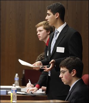 Sylvania Southview student Chris Ellis, left, objects to a question by St. John's Jesuit student John Banoub during the competition. Seated in the foreground is Harry Thaman of St. John's Jesuit. Two teams from  Southview advanced to the regional meet, as did one each from Perrysburg and St. Ursula.