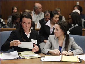St. Ursula students Jessica Cetnar, left, and Lindsay Carr, both acting as attorneys, review their case in the courtroom.