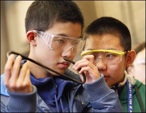 Hao Jiang, left, smells a piece of metal as Jia Rong Cai watches. The children have attended a school board meeting in Rossford, the Imagination Station downtown, and the Henry Ford Museum in Dearborn, Mich.