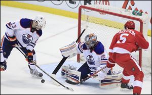 Edmonton Oilers goalie Nikolai Khabibulin (35) pushes the puck toward teammate Cam Barker (13) after a shot by Detroit Red Wings defenseman Nicklas Lidstrom (5) during the second period.