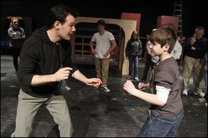 Nate Mitchell, left, a resident artist at the Purple Rose Theater in Chelsea, Mich., instructs Joseph Pilrose, a fifth grader at Douglas Road Elementary, in stage fighting at a rehearsal for the musical. Mr. Mitchell is an actor and choreographer. 