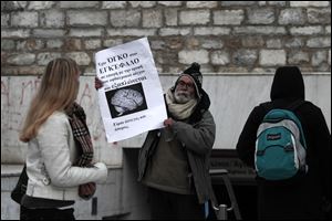 At a metro station in Athens, a man displays a banner reading 'I have a brain tumor -- I'm jobless and homeless' as anger mounts at prospects of more economic pain.