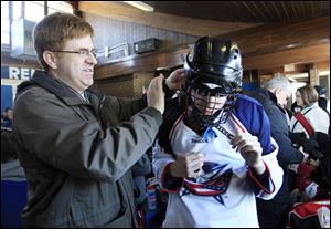 Joe Witalec helps his son Joshua, 14, a player on the team dubbed the Columbus Blue Jackets, with his gear before taking the ice. The first day of a round-robin tournament was Saturday.