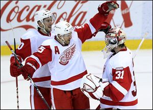 Red Wings goalie Joey MacDonald, right, celebrates with teammates Niklas Kronwall (55) and Drew Miller (20) after a shootout win.