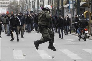 A policeman in riot gear tries to avoid a stone thrown by a protester during clashes in Athens,  where at least eight officers and two members of the public were injured. At least six people were arrested.