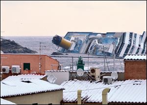 Snow covers the rooftops of the houses overlooking the harbour of the Tuscan island of Giglio, Italy, Saturday as the grounded Costa Concordia cruise liner still lays stricken in background.