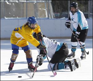 Megan Parker, left, of the Michigan FAR Flyers, mixes it up with Kavon Outerbridge of the Detroit MORC Stars during one of the games at the rink in Ottawa Park in Toledo. The tourney continues Sunday.