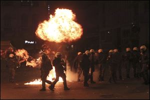 A petrol bomb explodes over riot police during clashes in Athens Sunday. Riots engulfed central Athens and at least 10 buildings went up in flames in mass protests late Sunday as lawmakers prepared for a historic parliamentary vote on harsh austerity measures demanded to keep the country solvent and within the eurozone. 