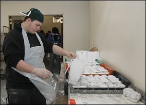Josh Hinkle of Toledo, a volunteer, fills an order for a mixed half-dozen paczki. The annual paczki sale in the old Lagrange neighbhood — Lagrinka in Polish — continues Monday and Tuesday.