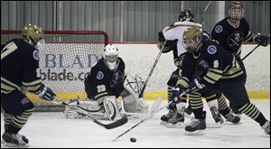 St. John’s goaltender Mike Barrett defends as Caleb Hauenstein and Ian Rapp try to clear the puck against Whitmer.