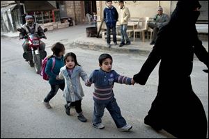 A woman leads a group of children along a street in Kafar Taharim, north Syria, where the Free Syrian Army has maintained control, and a normal lifestyle goes on. Government forces have focused their attacks elsewhere.