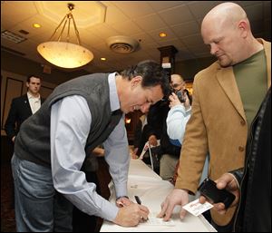 Republican presidential candidate Rick Santorum signs a pamphlet given to him by Samuel Joseph Wurzelbacher after a rally at the Holiday Inn French Quarter, Tuesday.