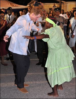 Britain's Prince Harry, left, dances with a local woman Friday during a walkabout at a 