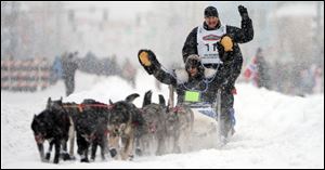 Defending champion John Baker, standing, was a few miles behind the leaders a day into the 40th Iditarod.