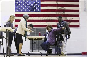 Poll worker, Dollie Scott, center, points the way for voters who cast their ballots on Tuesday in Atlanta.  