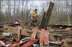 Jonathan Foster tosses debris from his ruined barn in Mount Olive in southern Ohio, where a tornado struck Friday, killing 3 people and damaging nearly 300 structures.