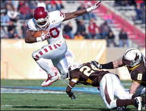 Temple running back Bernard Pierce (30) leaps over Wyoming defensive back Kenny Browder (24) and linebacker Brian Hendricks (8) in the 2011 New Mexico Bowl in Albuquerque, N.M.