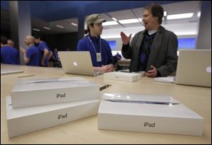 A customer talks with an Apple worker, in blue, inside an Apple store on the first day of the launch of the new iPad, in San Francisco. A research firm that has taken apart a new iPad says it's more expensive to make than the previous version was when it launched a year ago.