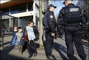 French Police officers stand guard at the entrance of a Jewish school in Paris Monday after a gunman opened fire killing four people in Toulouse, southwestern France. 