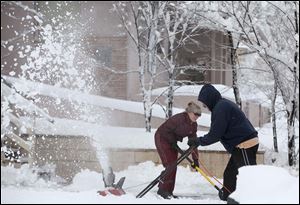 Two Flagstaff, Ariz., residents try to clear their sidewalk even as snow continues to fall. A reporting service said 12 to 18 inches fell on the city Sunday, and a hard freeze made roads extremely slippery.