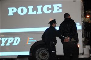 A police officer escorts one of the dozens of Occupy Wall Street protesters arrested in New York City’s Zuccotti Park to a waiting van. Some protesters at the anniversary rally claimed police gave them very little notice before they stormed the park late Saturday.