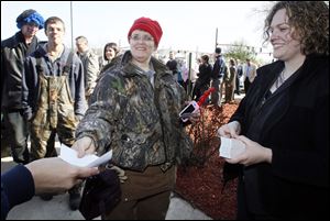 Cindy Zajac of Toledo is first in line to receive the gift card from Brooks VanKirk, right, marketing coordinator for Max & Erma’s restaurant. Directly behind Ms. Zajac is her son Austin Snow, 20.